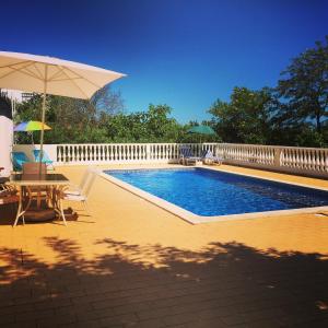 uma piscina com uma mesa e um guarda-sol em Vila Flora em Santa Bárbara de Nexe