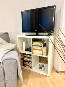 a tv on a white stand with books at Apartment Simona - Old Town in Bratislava
