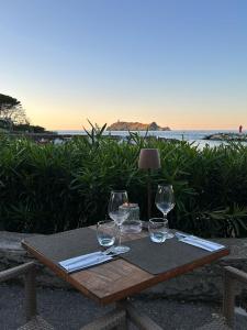 een tafel met wijnglazen op een tafel met het strand bij Hôtel Restaurant Petra Cinta in Barcaggio