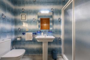 baño de azulejos azules con lavabo y aseo en CASA TURISTICA LA PARRA, en La Lastrilla