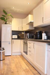 uma cozinha com armários brancos e um frigorífico branco em Modern 2 Bedroom Apartment Notting Hill Gate/Kensington em Londres