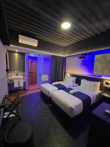 2 camas en una habitación con luces moradas en B Hotel Kuala Lumpur, en Kuala Lumpur