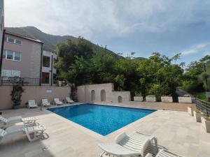 a swimming pool with chaises and chairs next to a building at La vita e bella in Prčanj