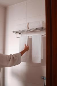 a person reaching for towels on a towel rack in a bathroom at Vida Plaza Hotel in Brasília