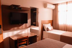 a room with two beds and a tv and a chair at Vida Plaza Hotel in Brasília