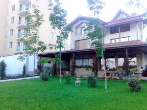 a house with a green yard in front of a building at Todorovi Guest House in Stara Zagora
