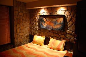 Un dormitorio con una pared de piedra con una cama y una pintura en Todorovi Guest House en Stara Zagora