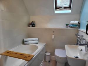 a bathroom with a tub and a toilet and a sink at Guest Homes - Clara Cottage in Bretforton