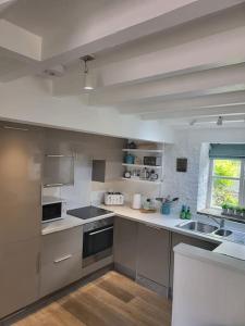 eine Küche mit Geräten aus Edelstahl und einem Fenster in der Unterkunft Host & Stay - Clara Cottage in Bretforton