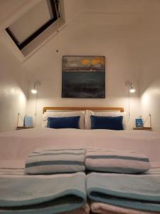 a bedroom with a large bed with blue pillows at Guest Homes - Clara Cottage in Bretforton