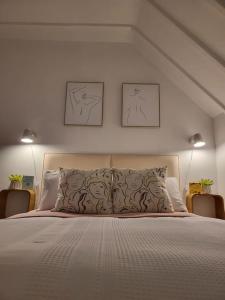 a bedroom with a bed with two pictures on the wall at Guest Homes - Clara Cottage in Bretforton