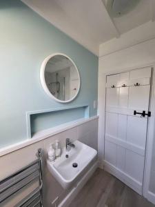 a white bathroom with a sink and a mirror at Guest Homes - Clara Cottage in Bretforton