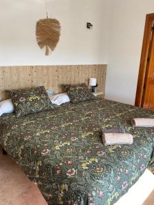 a bedroom with a bed with a green comforter at Hostal Espai Mediterrani in Puebla de Vallbona