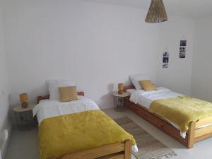 two beds in a white room with yellow sheets at Maison de ville très lumineuse in Civray
