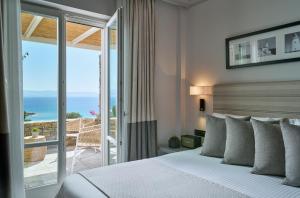 a bedroom with a bed and a view of the ocean at Summer Senses Luxury Resort in Logaras