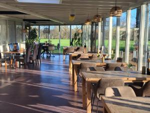 un restaurante con mesas y sillas de madera y ventanas en Landhotel Diever, en Diever