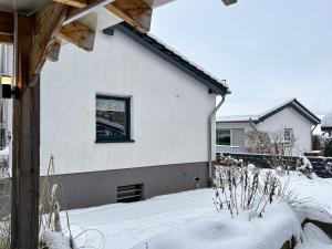 een wit huis met een raam in de sneeuw bij Am Höhlchen in Olsberg