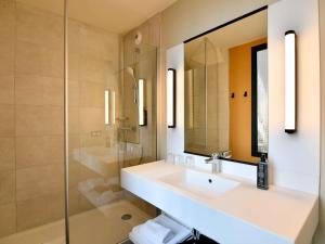 a bathroom with a sink and a mirror and a shower at ibis Styles Saint Nazaire Centre Gare in Saint-Nazaire