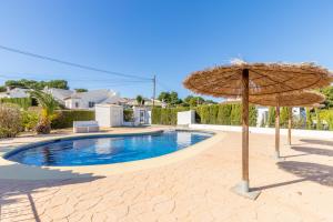ein großer Strohschirm und ein Pool in der Unterkunft Villa Family Moraira Style in Moraira