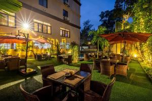 un restaurante con mesas y sombrillas en un patio en Best Western Plus The Athena Hotel Kampala en Kampala