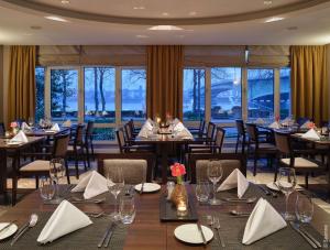 a dining room with tables and chairs and windows at Dorint Hotel Bonn in Bonn