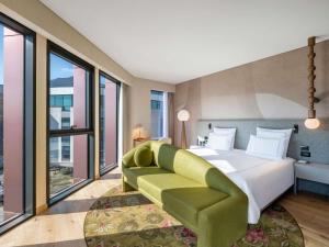- une chambre avec un grand lit et un canapé vert dans l'établissement Swissôtel Tbilisi, à Tbilissi