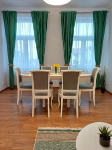 a dining room with green curtains and a table and chairs at Bella Casa - ApartHotel in Dej