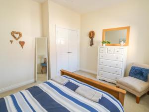 a bedroom with a bed and a chair and a mirror at 9 Seaford Sands in Paignton