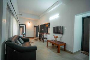 sala de estar con sofá y mesa en Cabana by GRHA - Charming Cottage at Kappad Beach, en Kozhikode