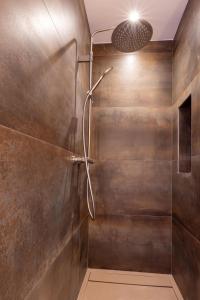 La salle de bains est pourvue d'une douche et d'un mur en métal. dans l'établissement La Manufacture D'oriano LES NUITS AU VILLAGE, à Montegrosso