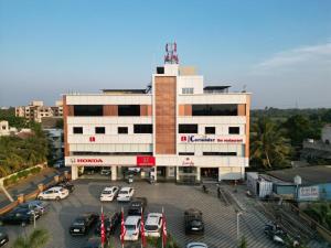 een gebouw met auto's geparkeerd op een parkeerplaats bij Lords Eco Inn Navsari in Navsāri