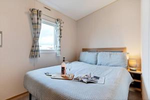 a bedroom with a bed with a bottle of wine at Tattershall Lakes: Sally's Superior Stay in Tattershall