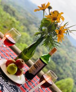 a bottle of wine and a vase with a flower at Bwindi Neckview Lodge in Buhoma