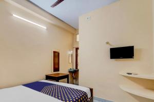 清奈的住宿－SPOT ON RKH Inn，卧室配有一张床,墙上配有电视。
