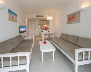 - un salon avec un canapé et une table dans l'établissement Coral Star Apartments, à Bahía de Sant Antoni