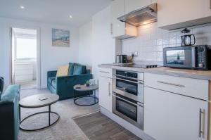 a kitchen with a stove and a microwave at Oasis - 2 Bedroom Apartment - Ocean Breeze in Port-Eynon