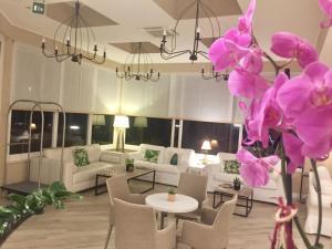 リド・ディ・イエゾロにあるHotel Nizza Frontemare Superior 3 Stelleのピンクの花と家具が備わる広いリビングルーム