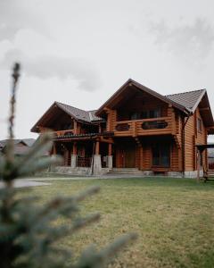 ein großes Holzhaus mit einem Hof davor in der Unterkunft Vila Mila in Mykulytschyn