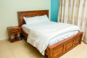 een slaapkamer met een bed met een houten frame en een tafel bij Spacious- Brb Homes Bukoto in Kampala