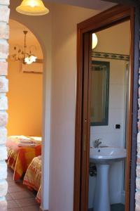 łazienka z umywalką, łóżkiem i lustrem w obiekcie Agriturismo Fonte Madonna w mieście Mirto