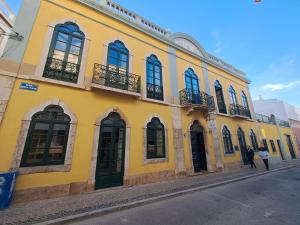 a yellow building with windows and balconies on a street at Tilia Hostel in Faro