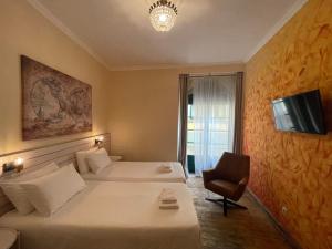 a hotel room with two beds and a chair at Tilia Hostel in Faro