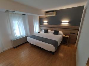 Hostal Alda Palencia Plaza في بالينثيا: غرفة نوم بسرير ابيض كبير مع وسادتين