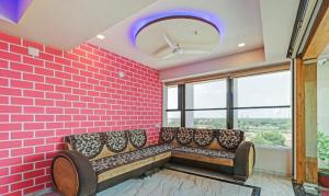 een kamer met een bank tegen een roze bakstenen muur bij Hotel Shree Regency Ahmedabad in Ahmedabad