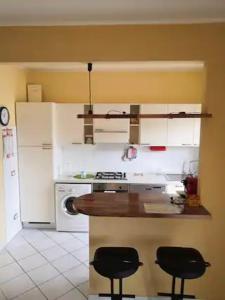 eine Küche mit einer Theke und zwei schwarzen Hockern in der Unterkunft Bilocale centrale 80 MQ, con terrazza abitabile in Tortoreto Lido
