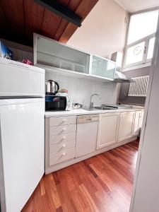 cocina blanca con electrodomésticos blancos y suelo de madera en StudiÒ Archet, en Aosta