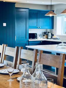 a kitchen with blue cabinets and a wooden table with wine glasses at Stanway House, 8 bedroom, 8 Bath in Cheltenham