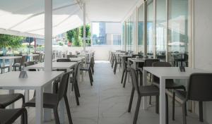 un ristorante vuoto con tavoli, sedie e finestre di Hotel Ninfea Cattolica a Cattolica