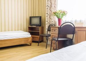 - une chambre avec un lit, une télévision et une chaise dans l'établissement Optima Sumy, à Soumy