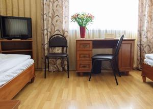 a bedroom with a bed and a desk and a tv at Optima Sumy in Sumy